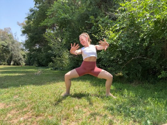 Personal trainer demonstrating fire pump exercise outside.