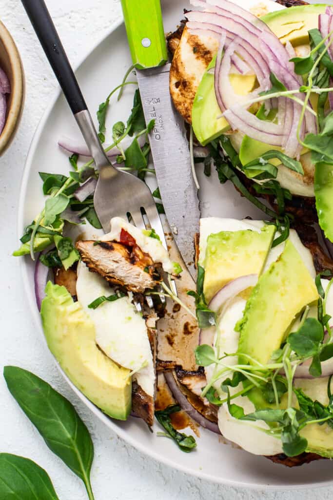 A plate with grilled chicken and avocado on it.