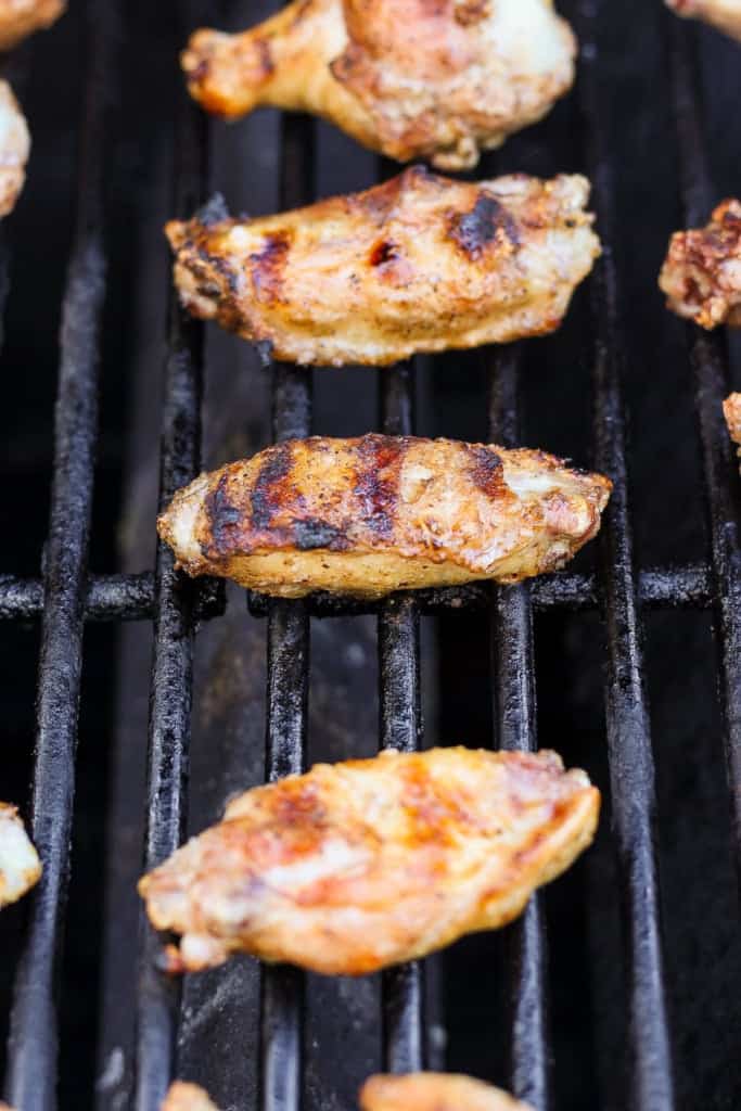 Grilled chicken wings on a barbecue grill with grill marks visible.