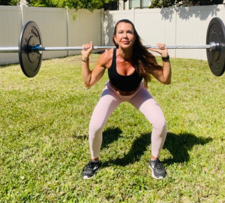 Personal trainer demonstrating barbell back squat