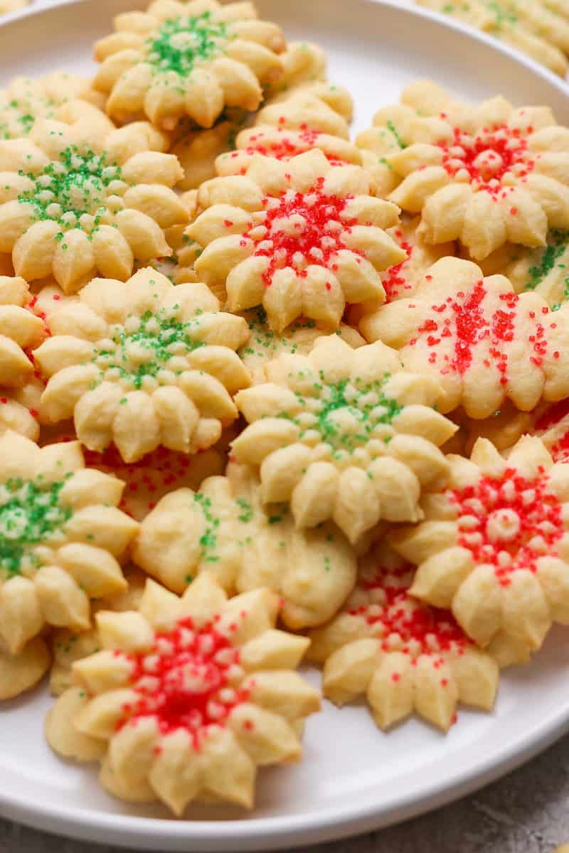 A plate of flower-shaped cookies decorated with red and green sprinkles.