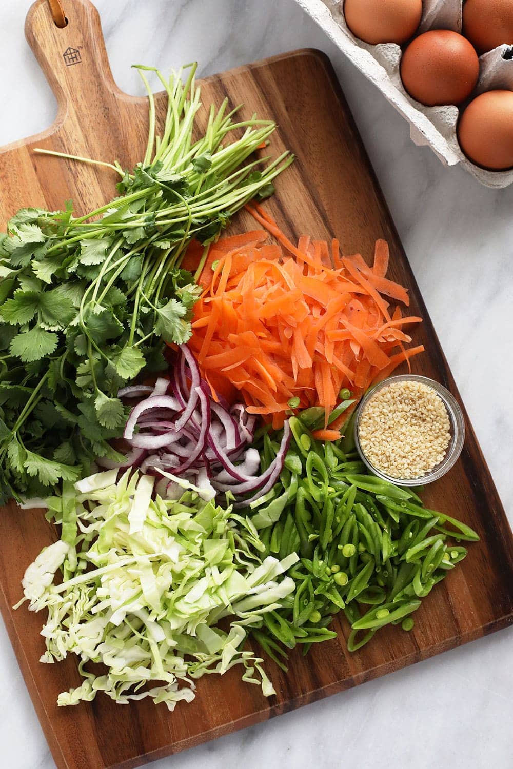 This vibrant Egg Roll in a Bowl recipe is packed with all the flavors you love in traditional egg rolls, but is deconstructed and served in a bowl for a healthy and delicious alternative. No deep frying! egg roll in a bowl recipe ingredients chopped on a cutting board