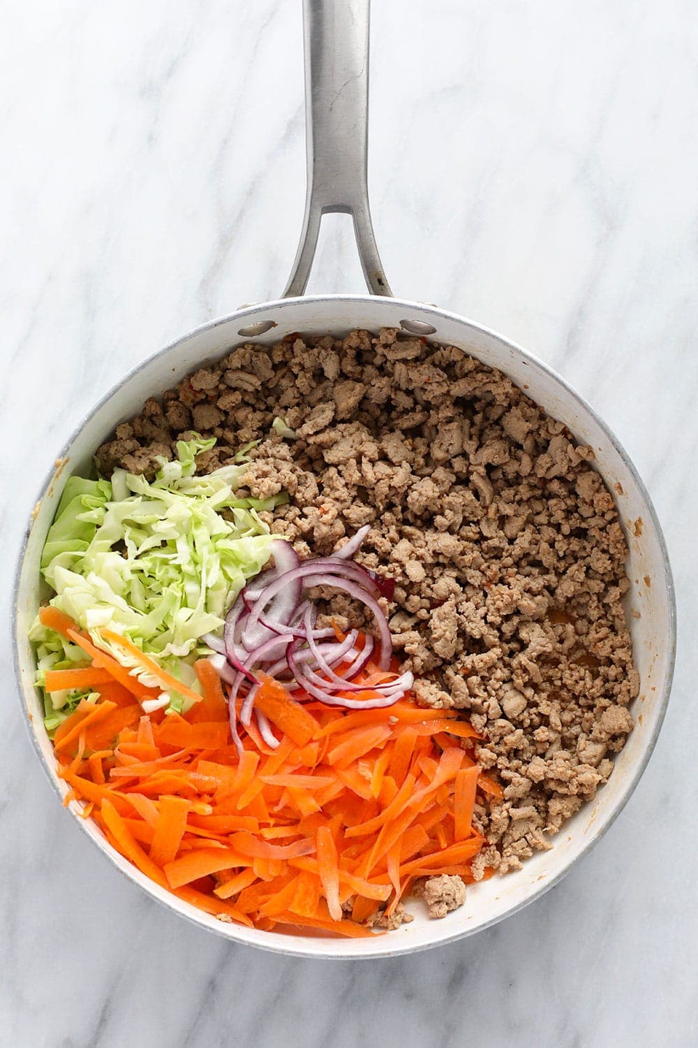 This vibrant Egg Roll in a Bowl recipe is packed with all the flavors you love in traditional egg rolls, but is deconstructed and served in a bowl for a healthy and delicious alternative. No deep frying! egg roll in a bowl recipe ingredients in a skillet ready to be sauteed