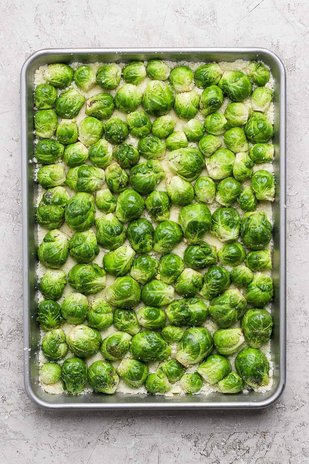 A baking tray filled with halved Brussels sprouts arranged in a single layer, ready to be roasted.