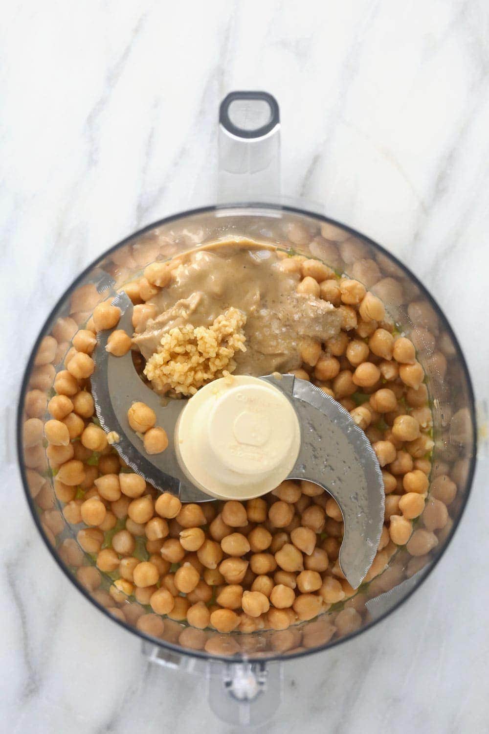 All those hummus flavors you love with a lemon garlic twist! Make this healthy lemon garlic hummus and get ready for all your dip dreams to come true. lemon garlic hummus ingredients in a food processor