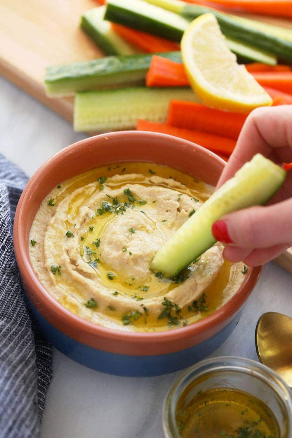 All those hummus flavors you love with a lemon garlic twist! Make this healthy lemon garlic hummus and get ready for all your dip dreams to come true. lemon garlic hummus in a bowl with a veggie dipped in it