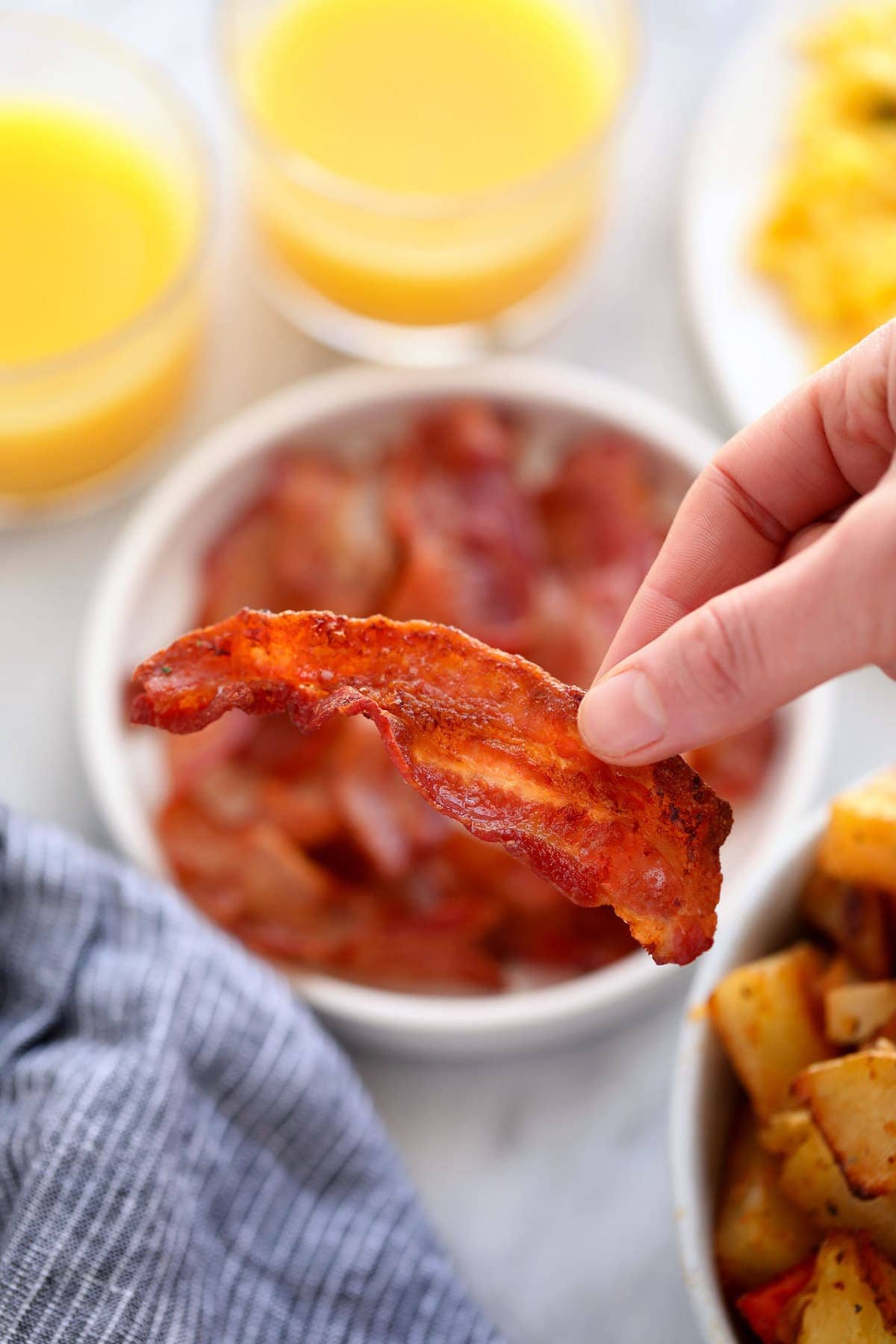Looking for a quick and easy air fryer bacon tutorial? In this post, we'll teach you how to cook bacon in the air fryer in just a few steps! holding bacon