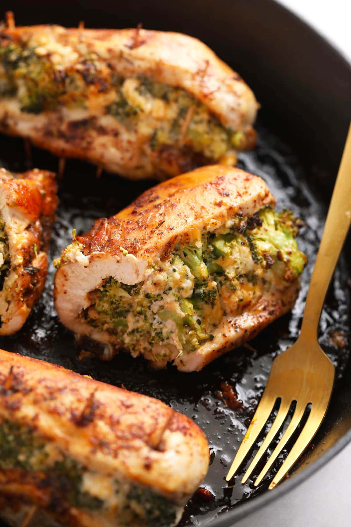 Broccoli and cheese stuffed chicken breast never tasted better! Our super flavorful chicken dry rub and easy broccoli and cheese filling make these stuffed chicken breasts deliciously flavor and protein packed. broccoli and cheese stuffed chicken breast in a cast iron skillet.