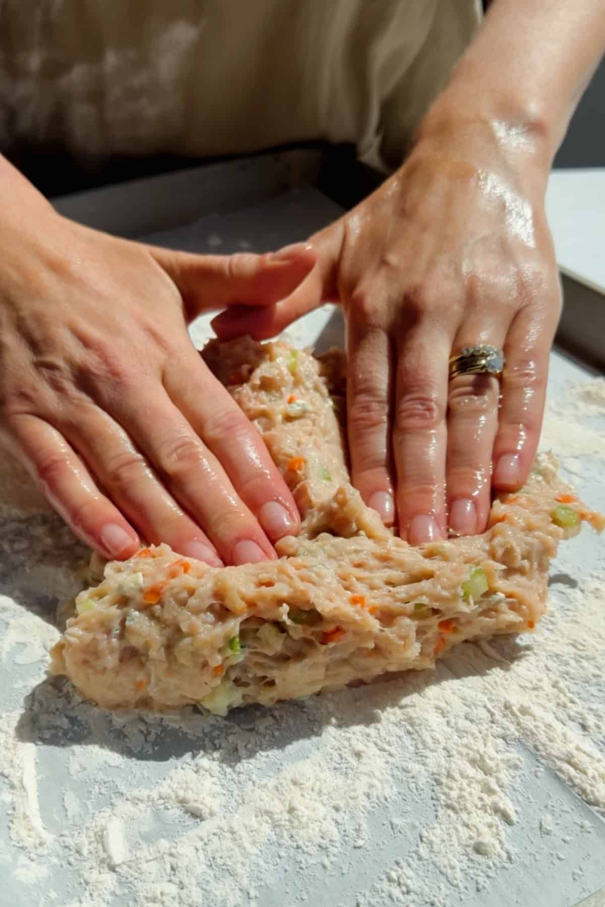 Pressing and shaping ground chicken protein bar mixture with vegetables on parchment paper