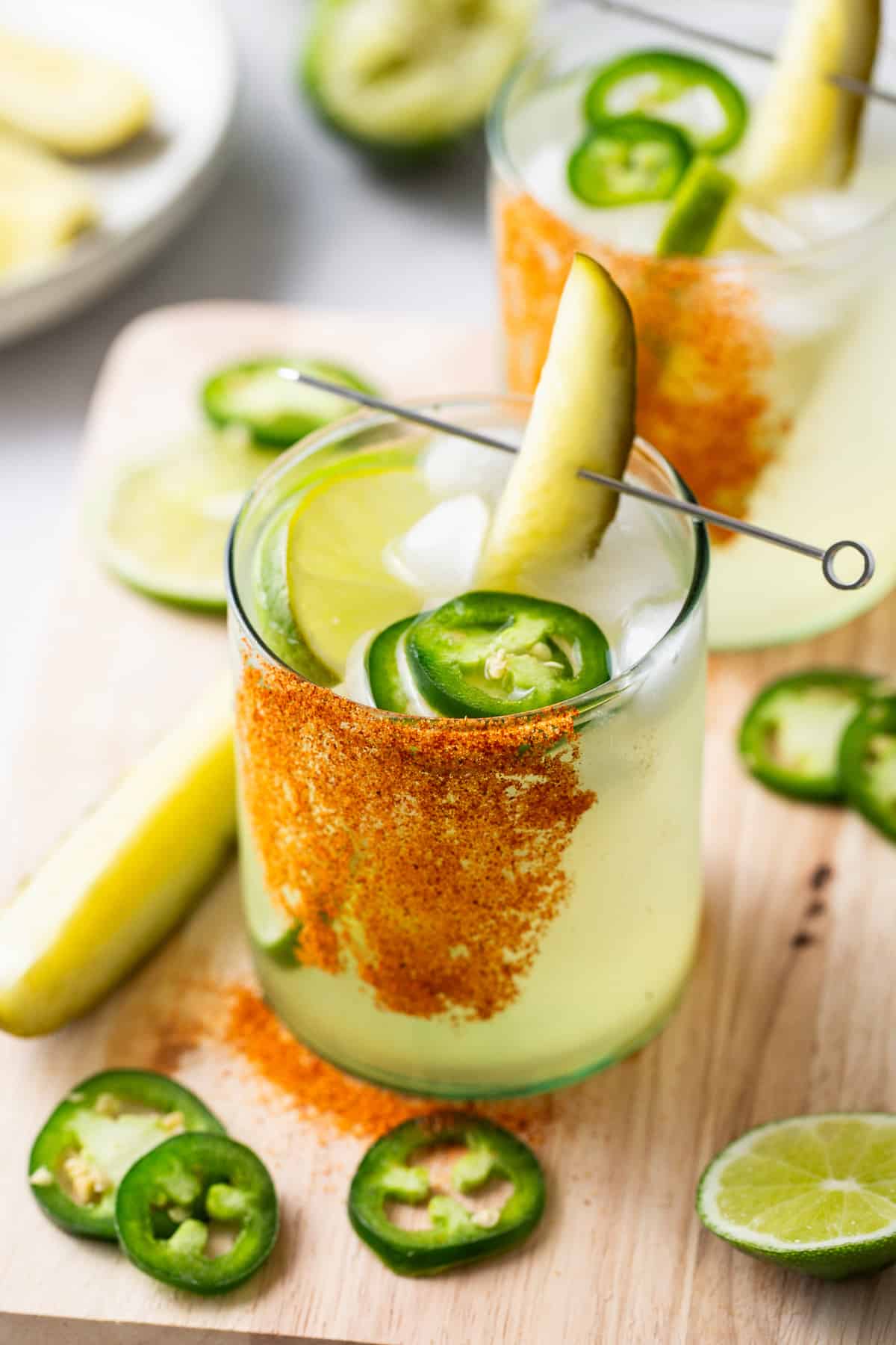 Two spicy pickle margaritas garnished with jalape&ntilde;o and lime.