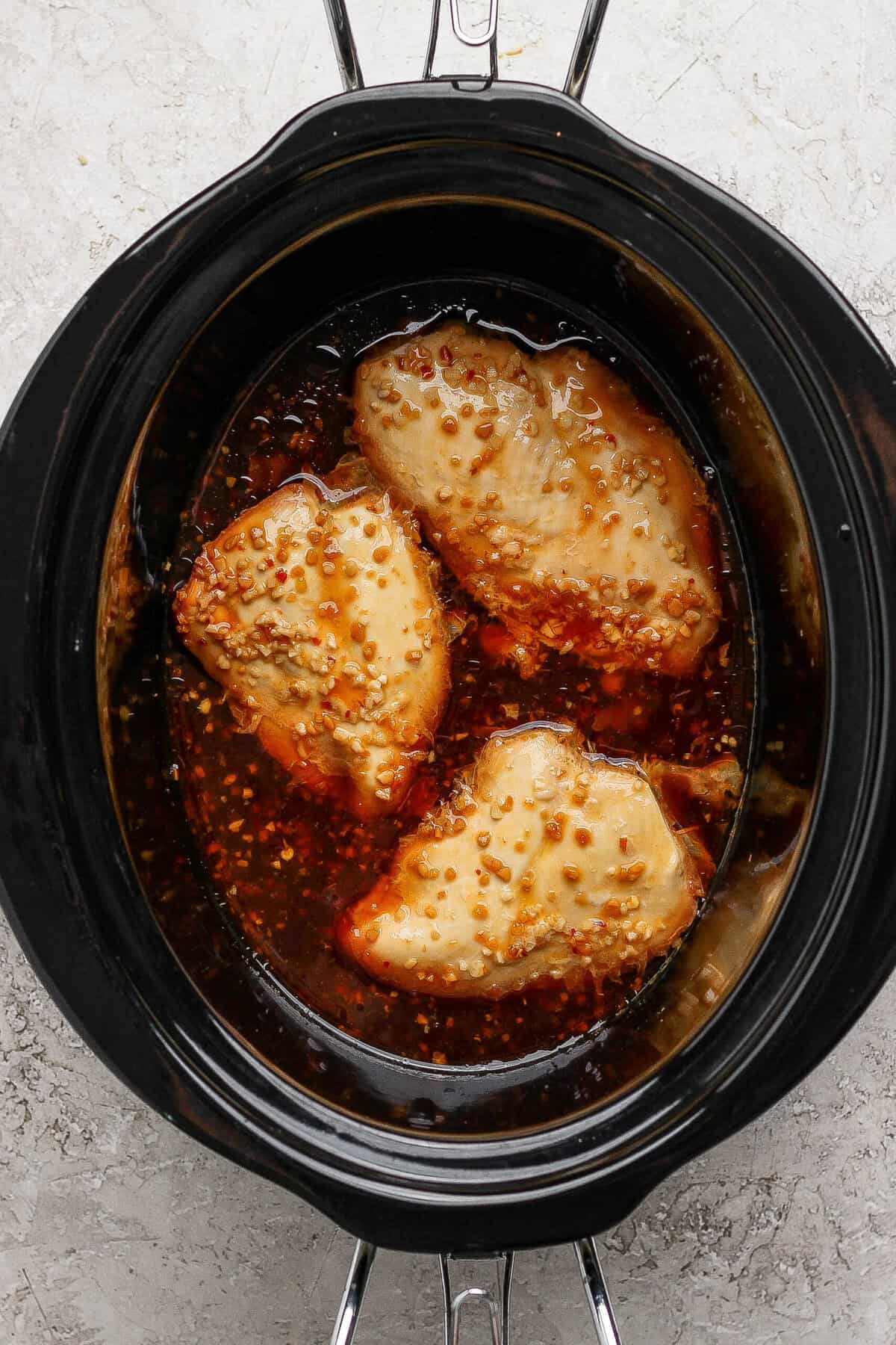 Honey garlic chicken breasts cooking in a slow cooker with sauce