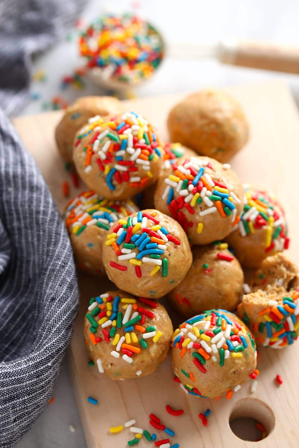 overhead shot of birthday cake protein balls piled on a plate with rainbow sprinkles