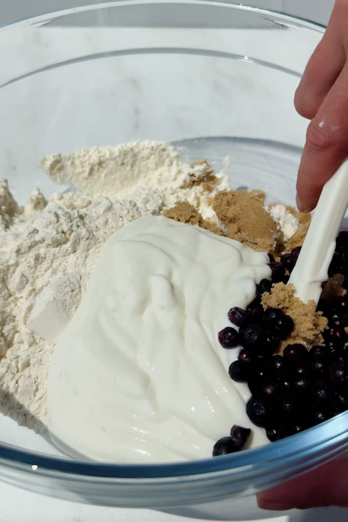 mixing flour cottage cheese blueberries and brown sugar in a bowl for blueberry biscuits