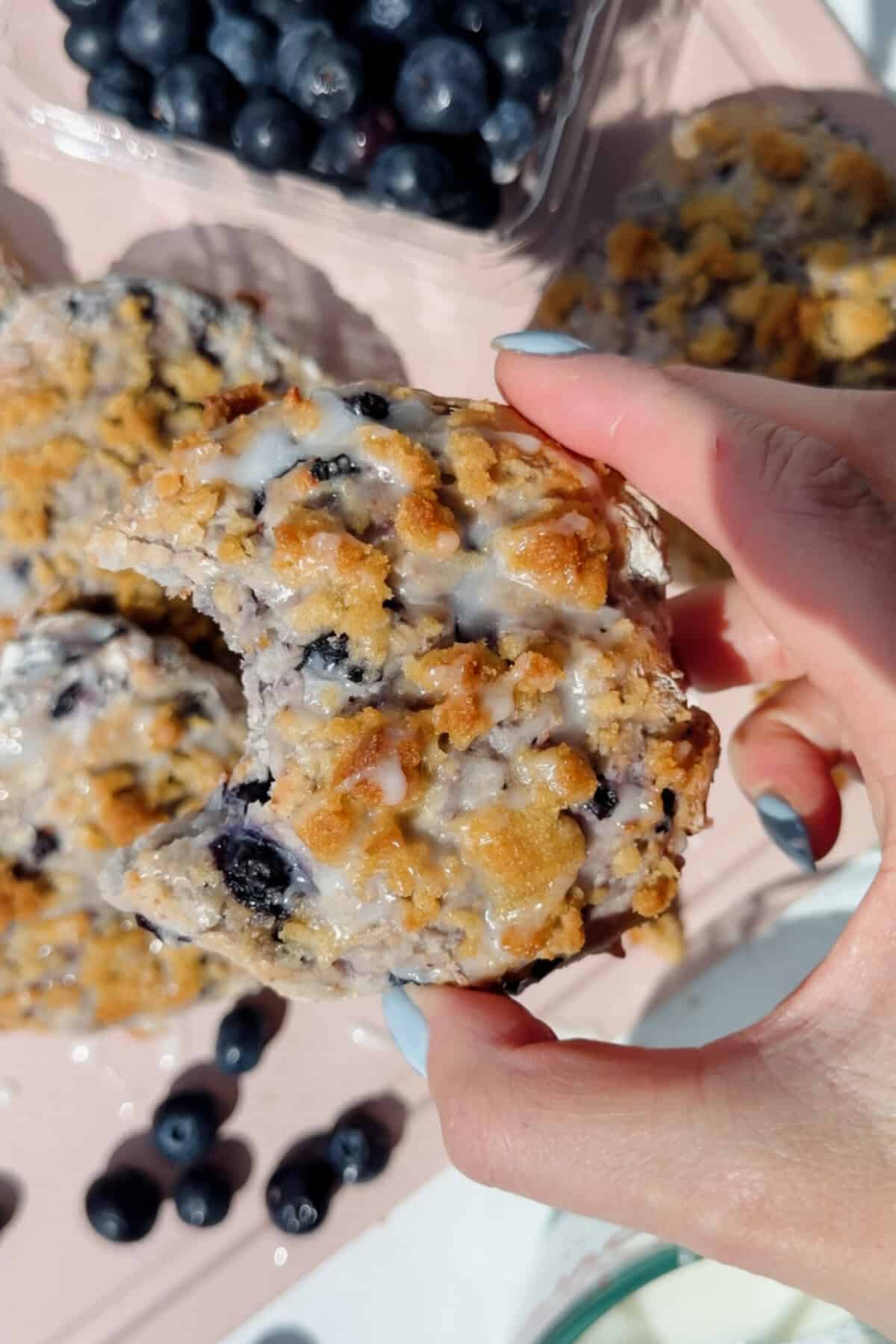 hand holding a blueberry cottage cheese biscuit with a bite taken out showing fluffy interior
