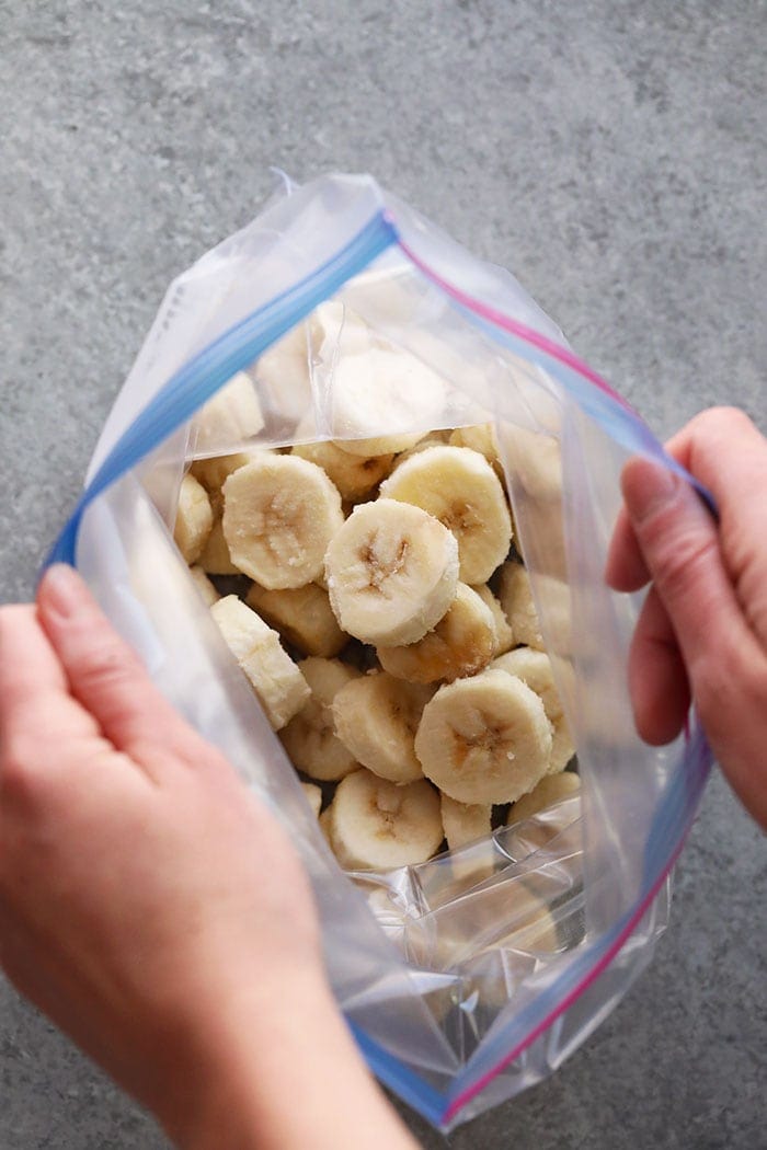 a person freezing bananas in a plastic bag