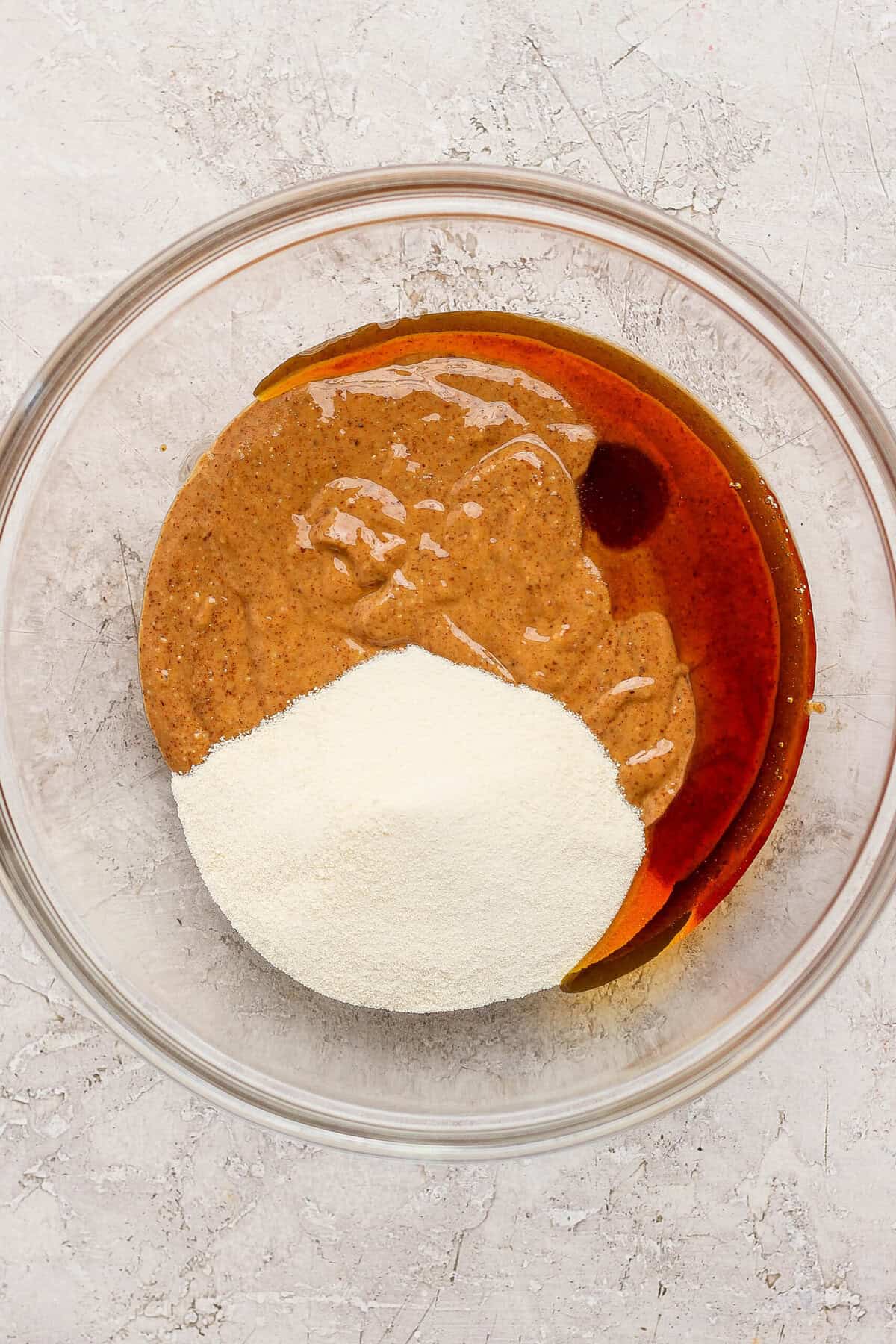 mixing almond butter maple syrup and protein powder in a glass bowl for thin mint protein bites