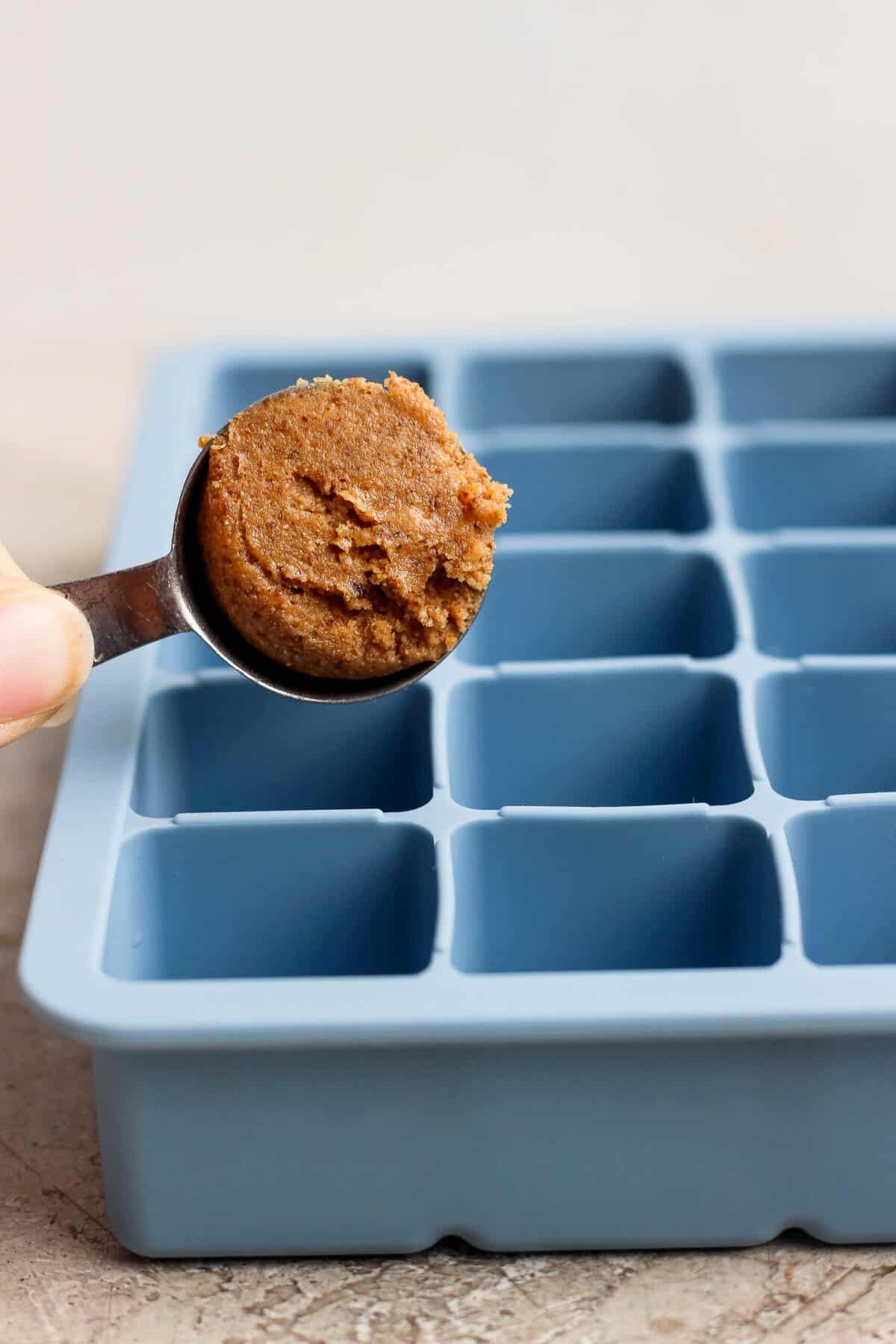 spooning protein bite mixture into a blue silicone ice cube tray