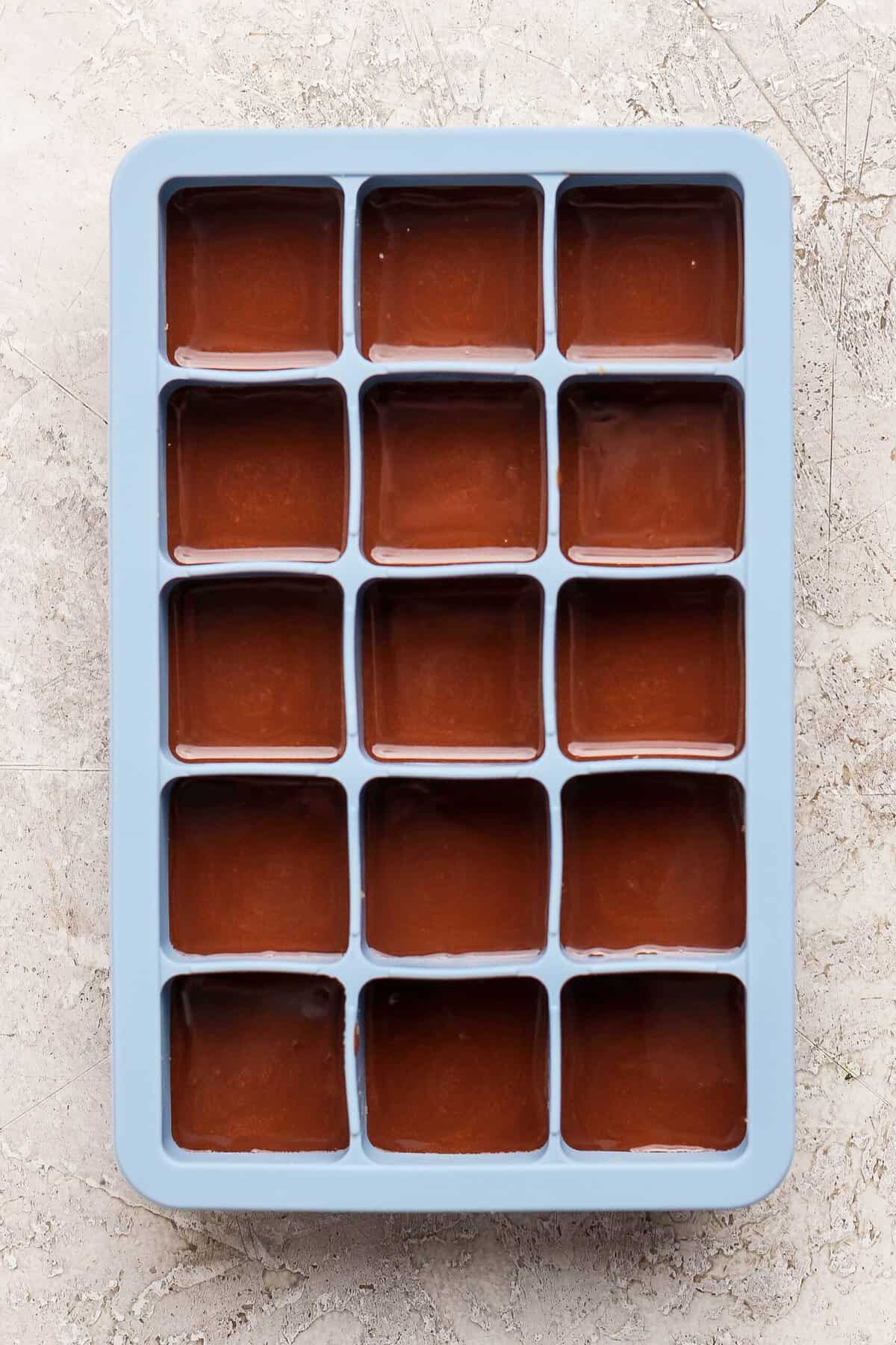 thin mint protein bites covered with melted chocolate layer in a blue silicone ice cube tray