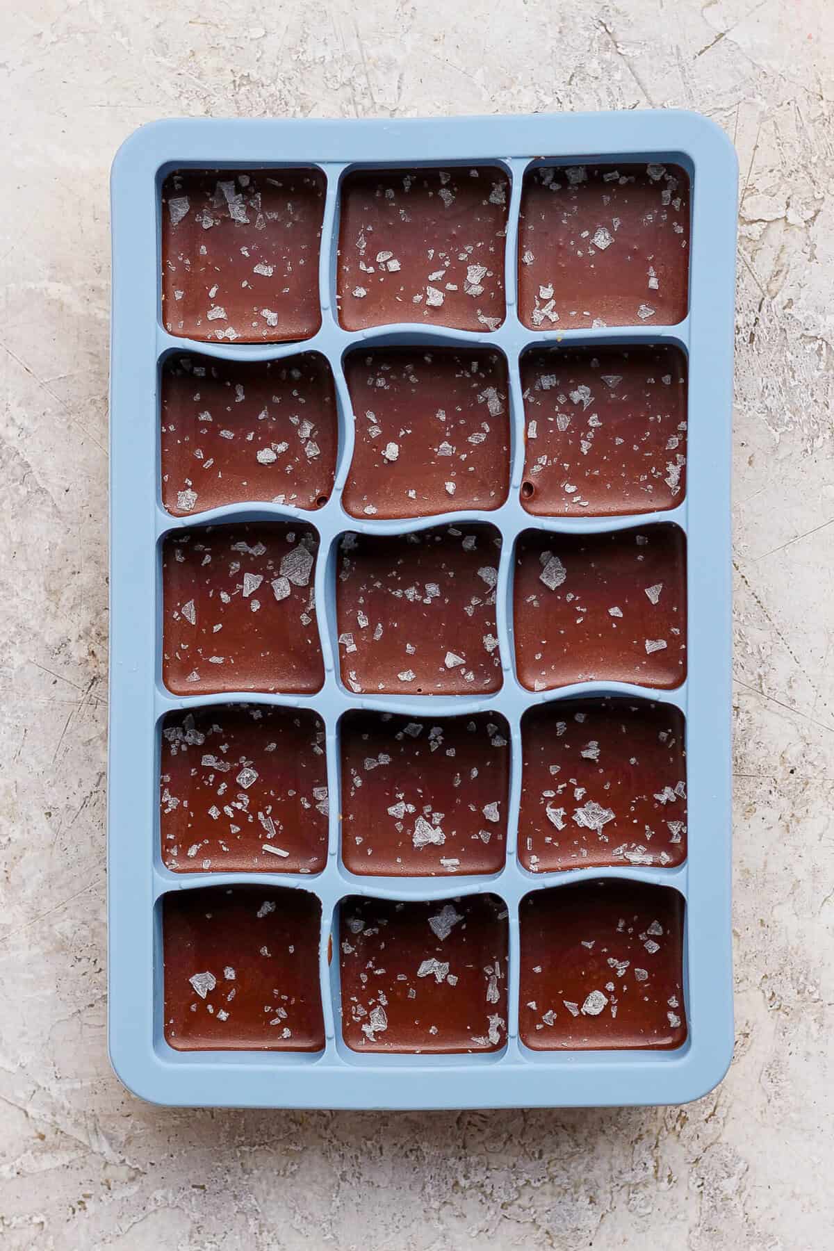 thin mint protein bites topped with flaky sea salt in a blue silicone tray before freezing