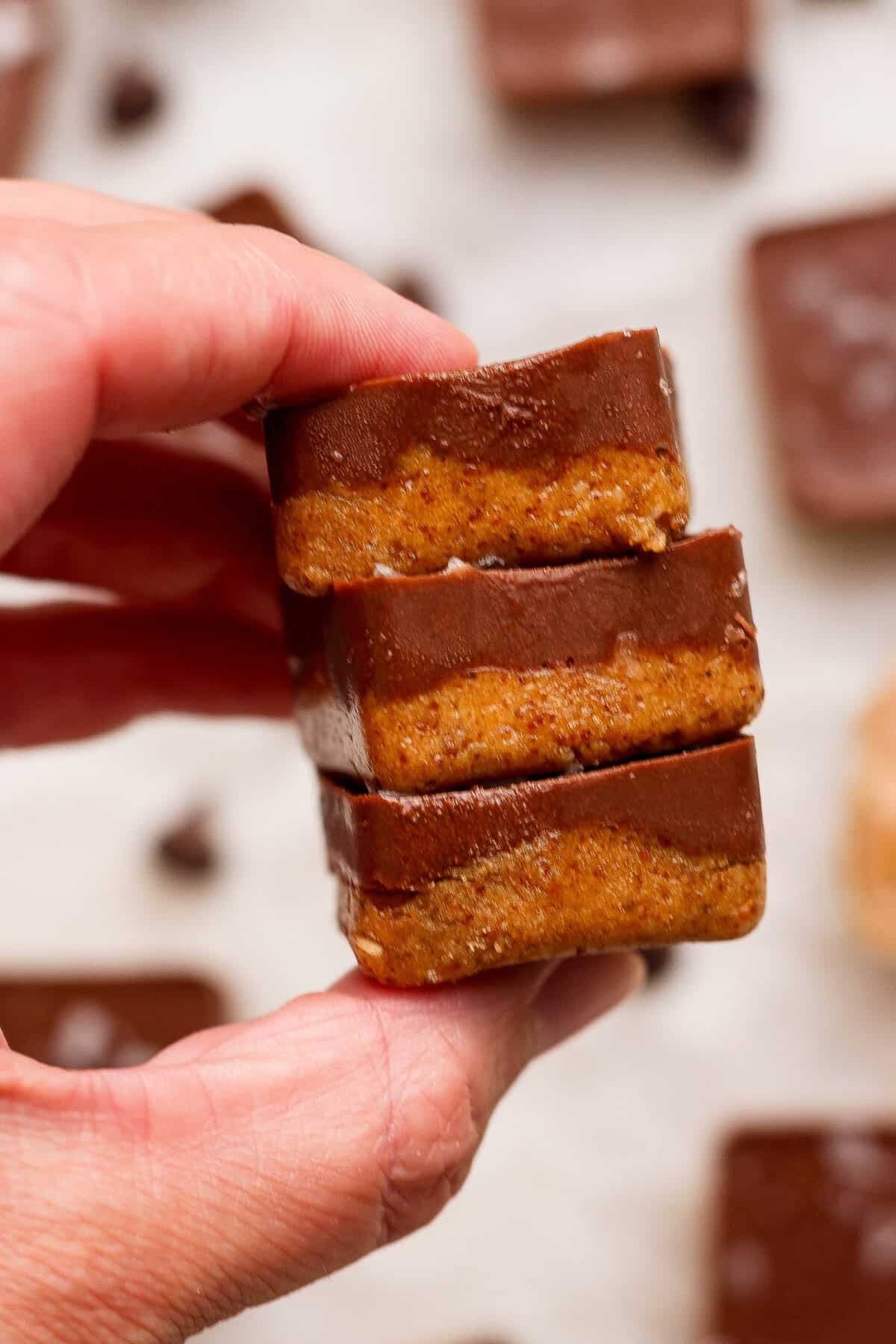 hand holding a stack of three no bake thin mint protein bites with chocolate coating