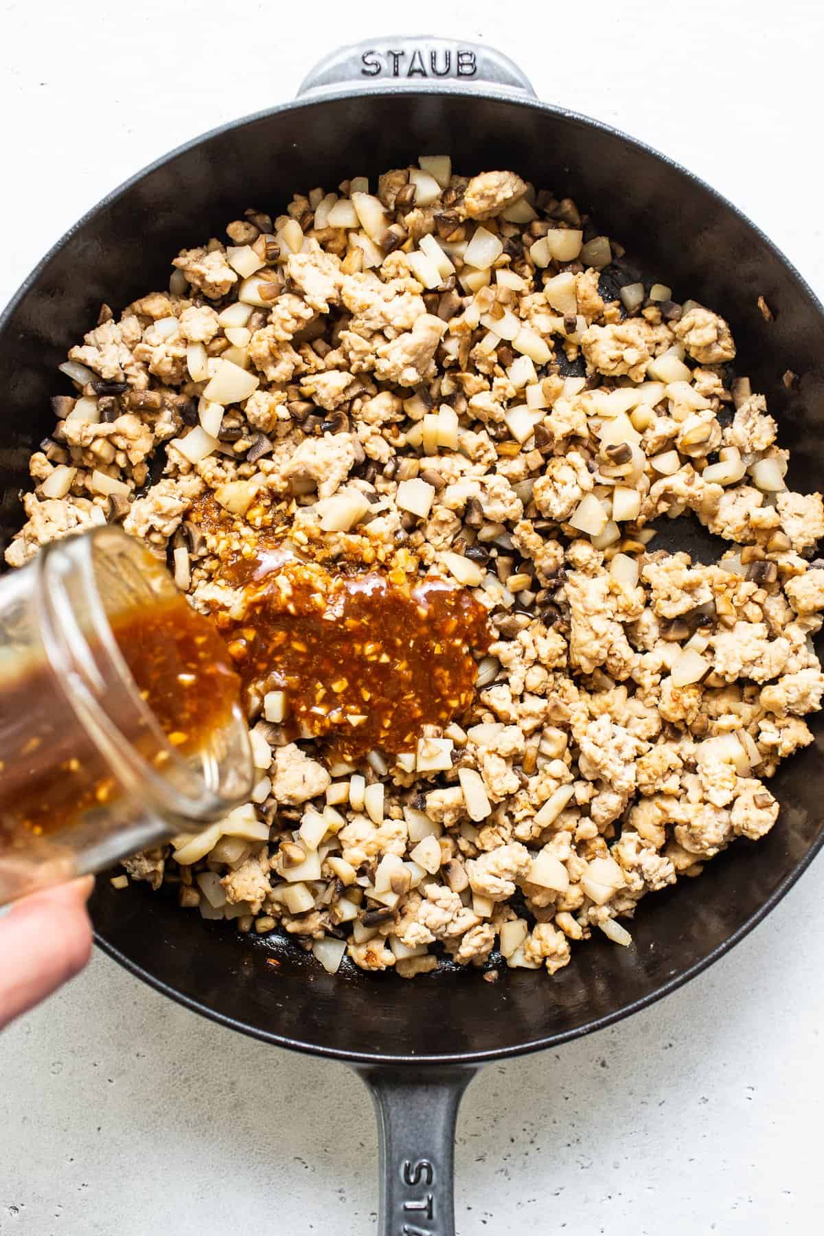 This copycat. PF Chang's Lettuce Wraps recipe is so easy to make in your own kitchen and comes together in less than 30 minutes! Pouring sauce over ground chicken for PF Chang's lettuce wraps.