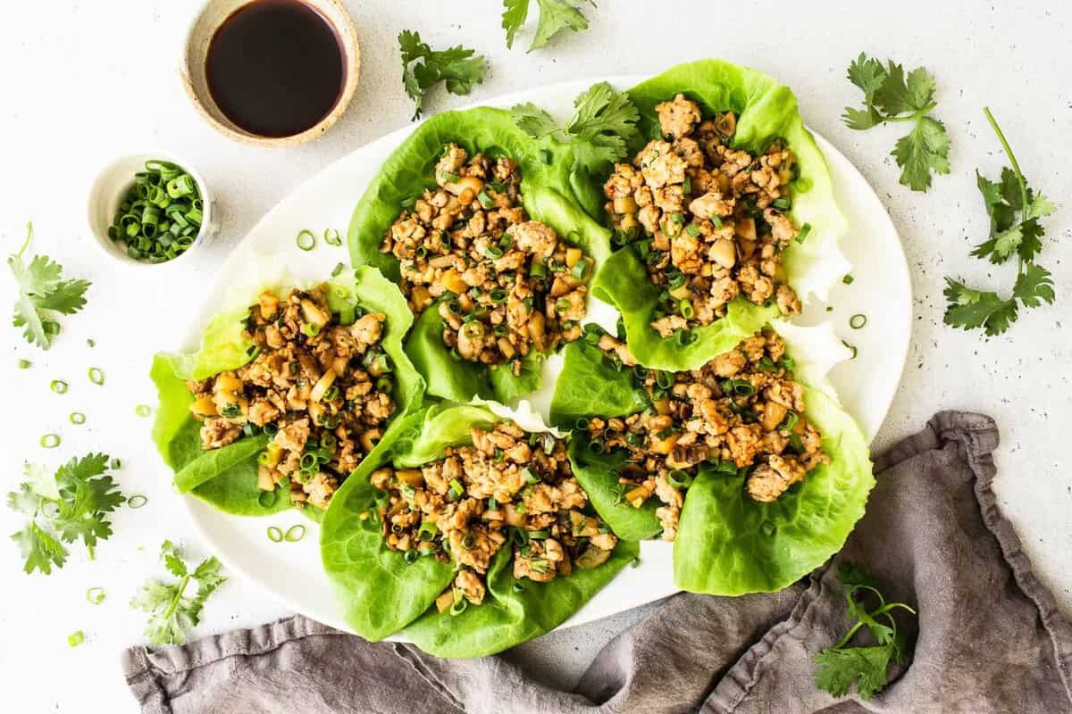 These copycat PF Chang's Lettuce Wraps are an easy at-home meal boasting with flavor that come together in less than 30 minutes! Chicken lettuce wraps on a serving platter with toppings.
