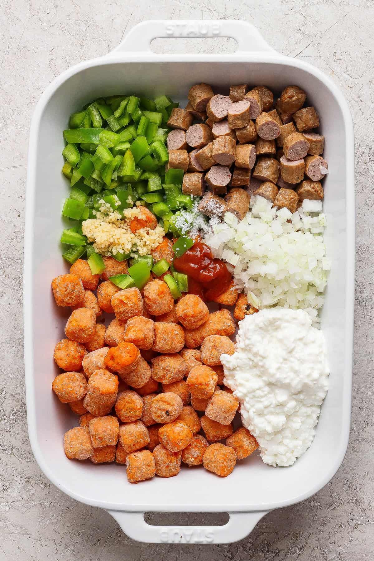 sweet potato tater tots sausage and vegetables in baking dish before adding eggs