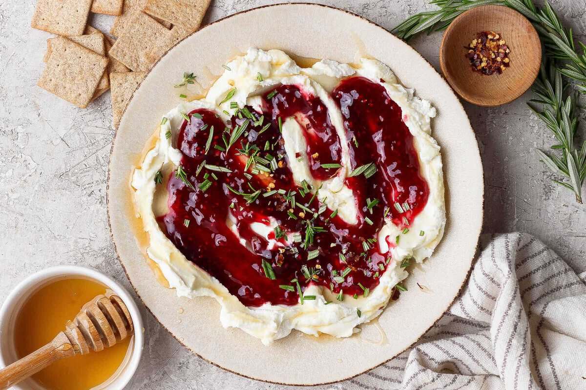 goat cheese dip topped with raspberry jam, fresh rosemary, and red pepper flakes served with crackers and hot honey