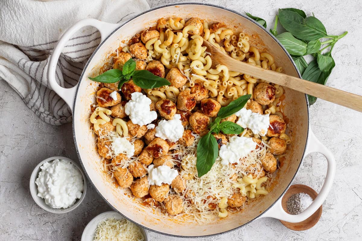 Skillet of mini cottage cheese meatballs and pasta with Parmesan, cottage cheese, and basil.