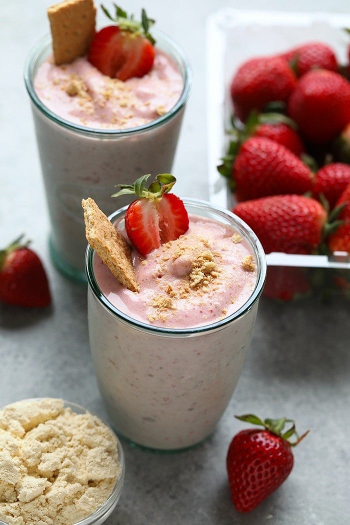 strawberry protein smoothie in a glass with graham cracker crumble on top