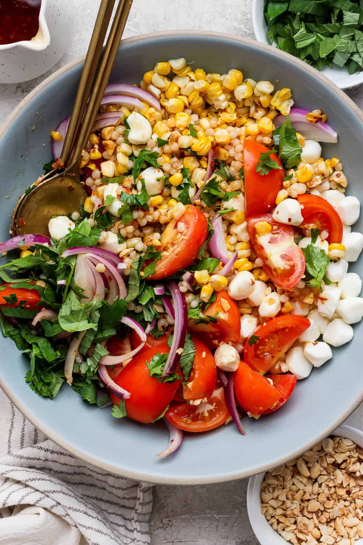 corn tomato salad served in a blue bowl with gold utensils