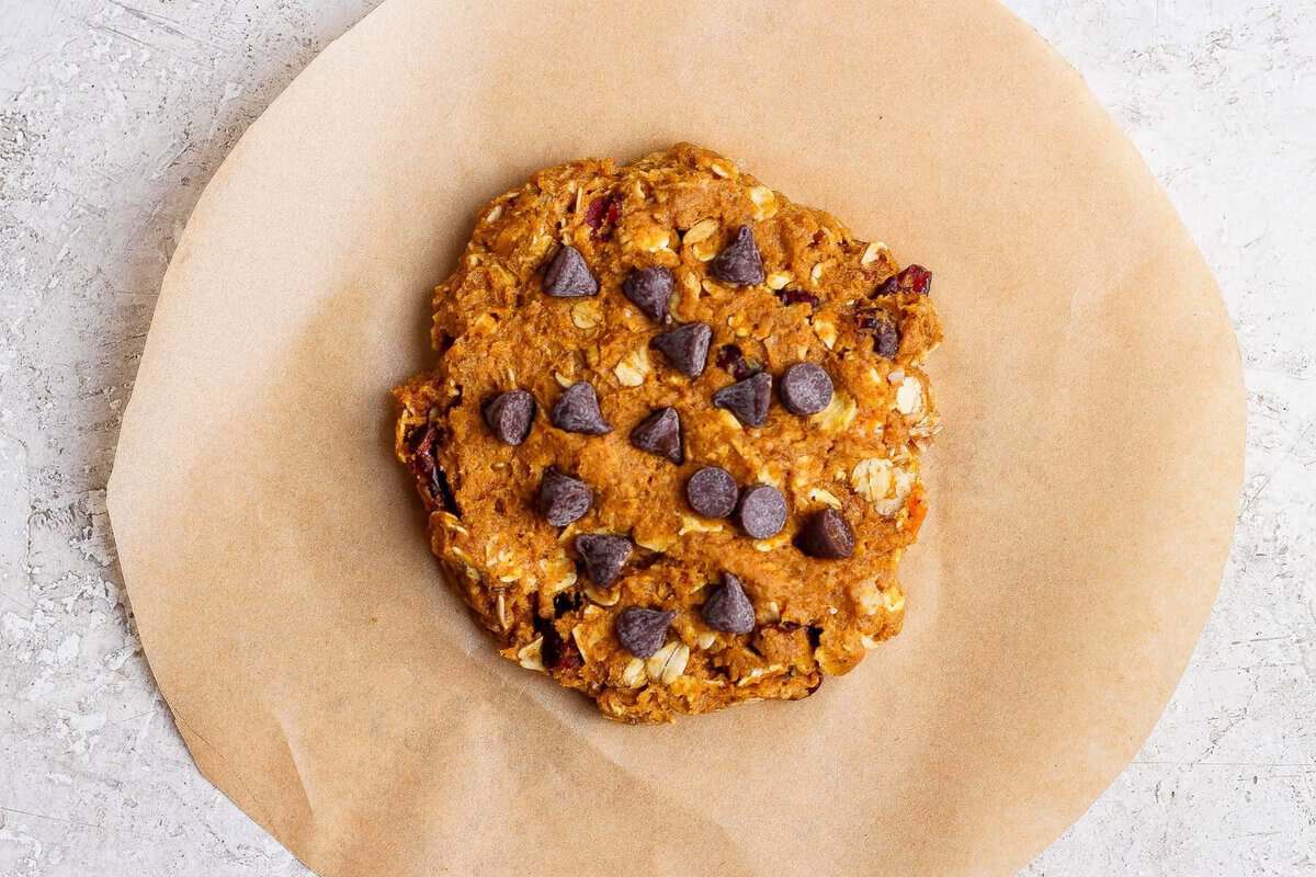 One pumpkin oatmeal cookie with chocolate chips on a round piece of parchment.