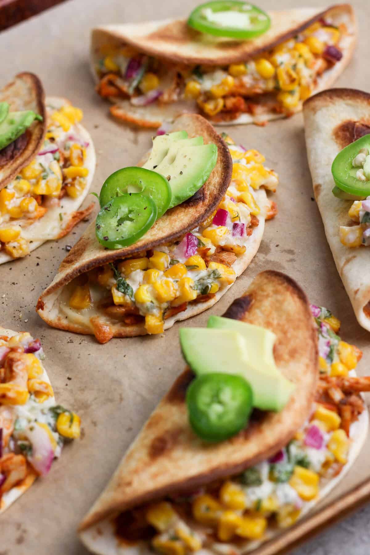 Crispy baked chicken tacos filled with creamy street corn salad and topped with avocado and jalape&ntilde;o.