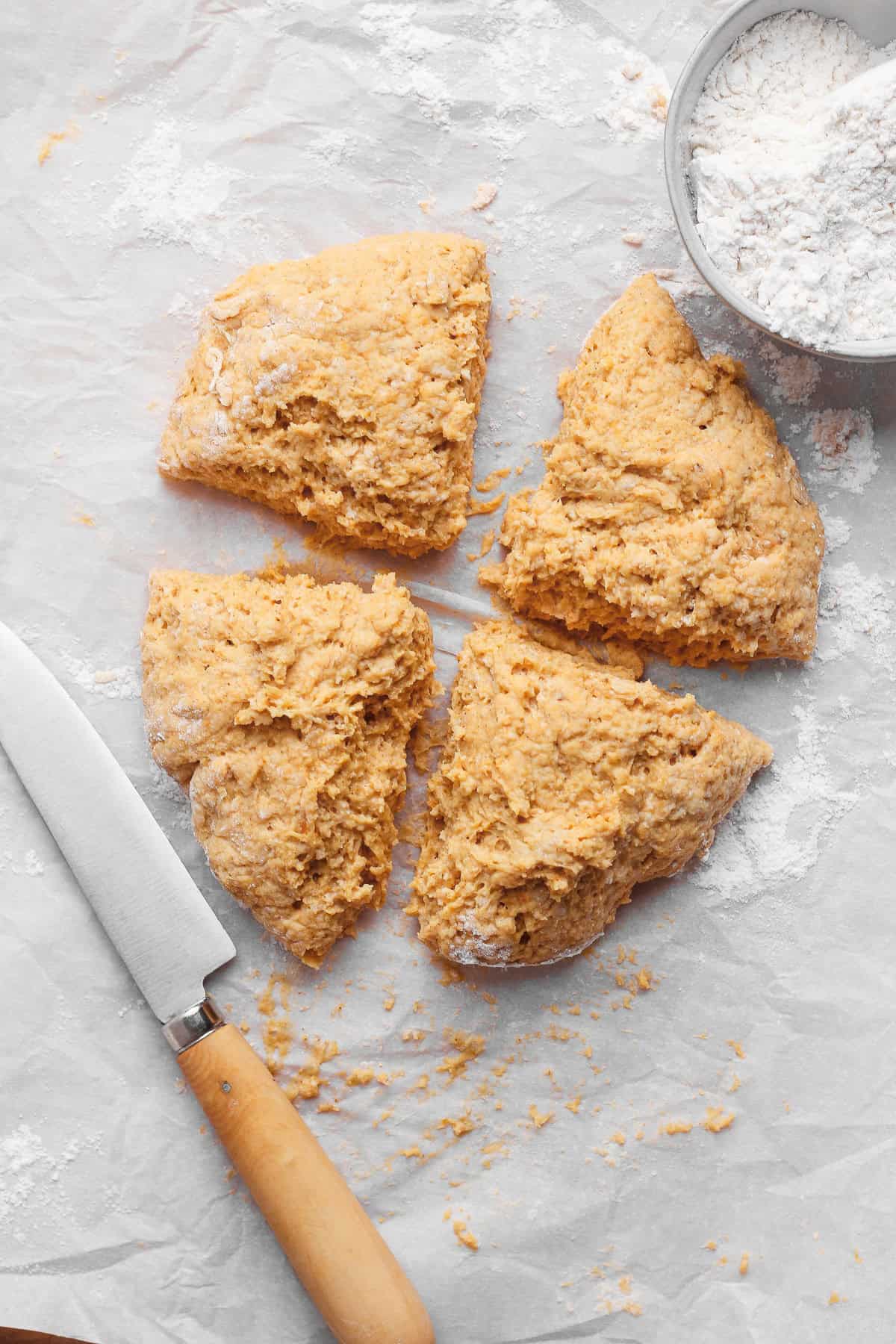 Pumpkin fritter dough cut into four equal wedges on a lightly floured work surface.