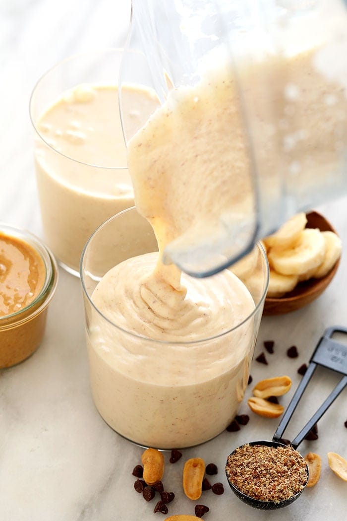 Pouring peanut butter banana smoothie into a glass
