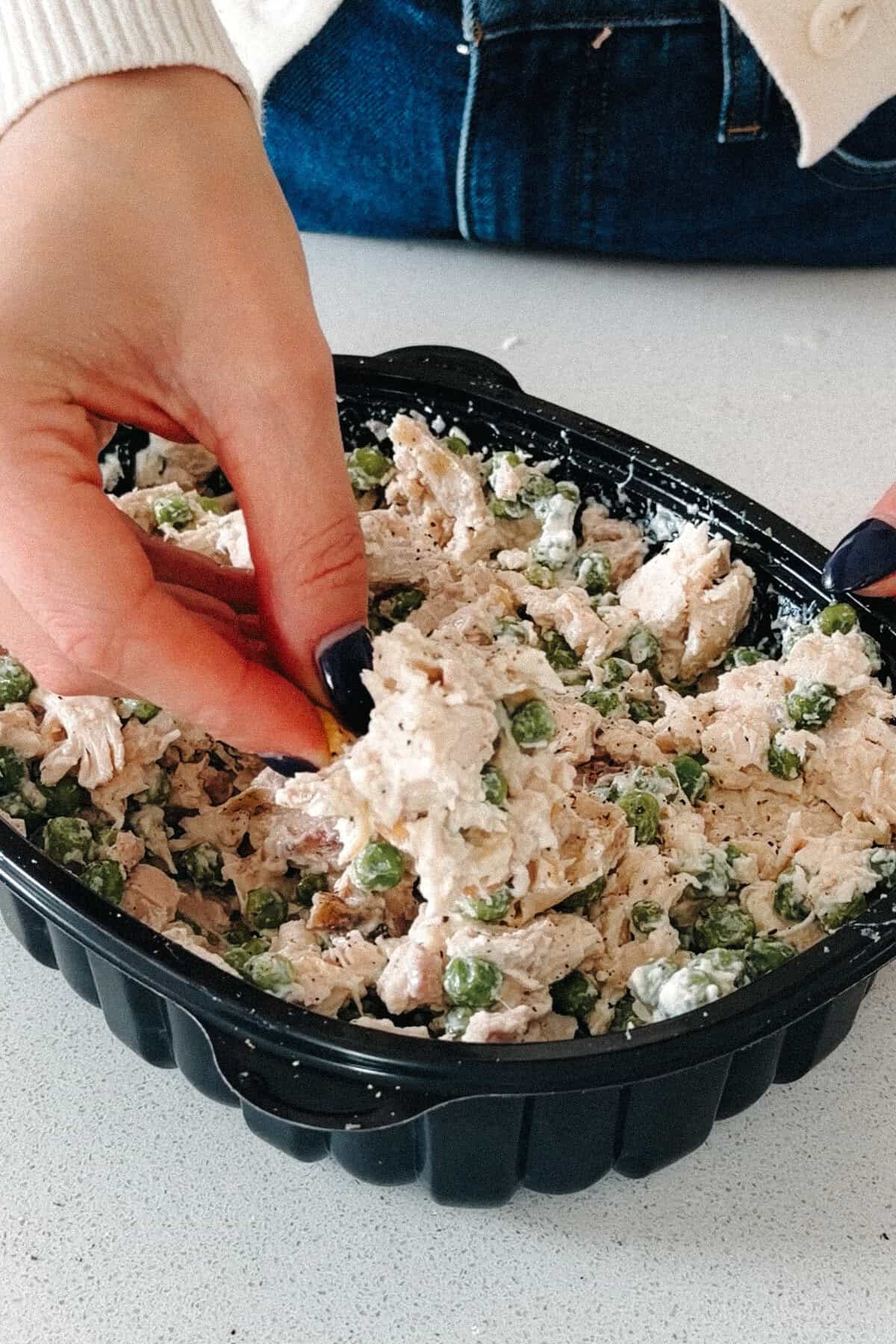 A serving of creamy chicken salad with peas lifted from its container.