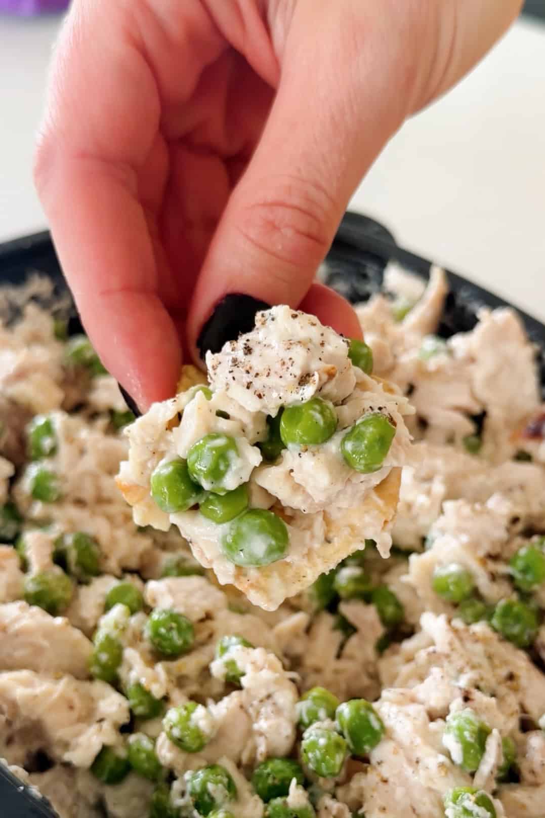 Close-up of a bite of creamy chopped chicken salad with green peas.