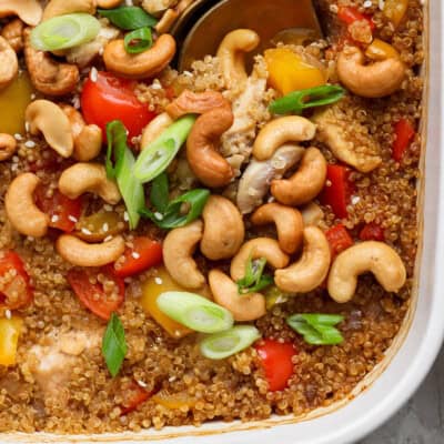Cashew chicken casserole with bell peppers, cashews, and green onions in a white dish.