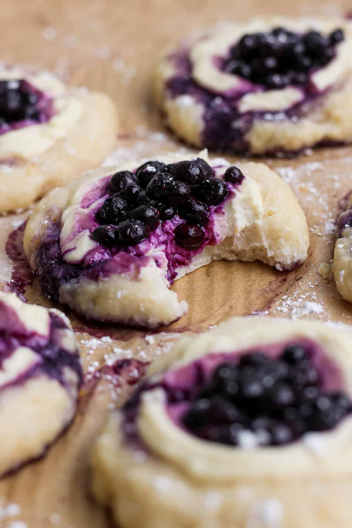 A bitten blueberry cottage cheese Danish showing the dough and creamy blueberry center.