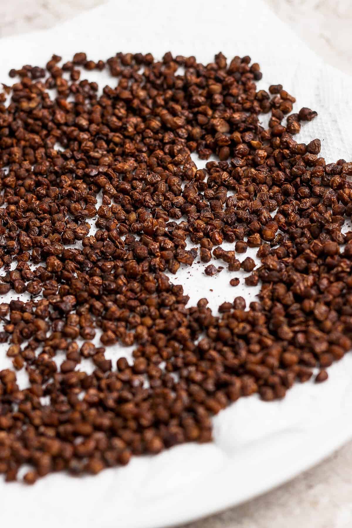 Crispy lentils spread in a single layer on a paper towel to cool.