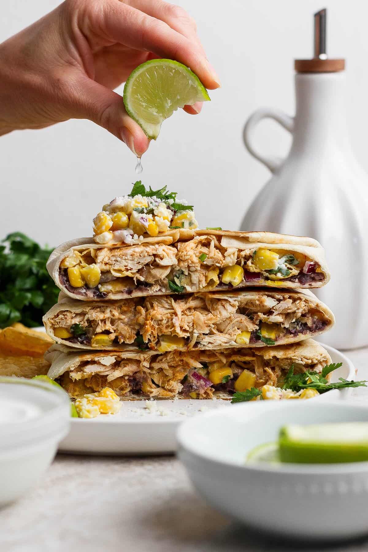 Fresh lime juice squeezed over a stack of street corn chicken crunchwraps.